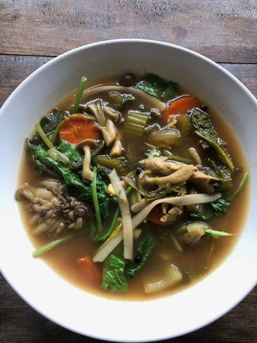 A bowl of broth with greens